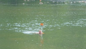Nathan Harris, of Allegheny Surveys, swims in place while locating river bottom cross sections downstream of the dam.