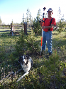 Survey dog 'Nash takes a break as the author marks the old pipe; the new pin is under the fence in the background.