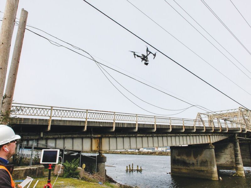 Kumpula (left) demonstrates an inspection maneuver for a remote pilot in training with a UAS near overhead utilities along the shut-down bridge.
