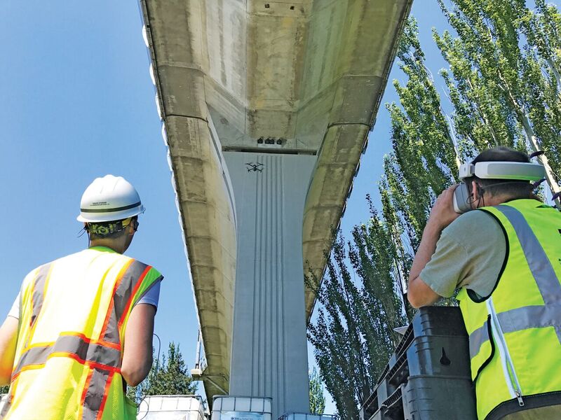 DEA’s remote pilot Ryan Reedy (left) and structural en- gineer/remote pilot Eric Ferluga (right) perform a structural inspection of a railway elevated guideway using HD video goggles. Not pictured is author Matt Kumpula who is ensuring that the flight is safe.