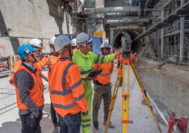 Working in the TBM access trench, a team uses a total station and handheld controller for automated measurement and data analysis.