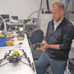 Applications engineer Jeff DeBoer demonstrates interchangeable payload options enabled by the “V” airframe of the new UAS, Falcon 8. Two models are offered: GeoEXPERT for surveying and InspectionPRO for industrial inspection.