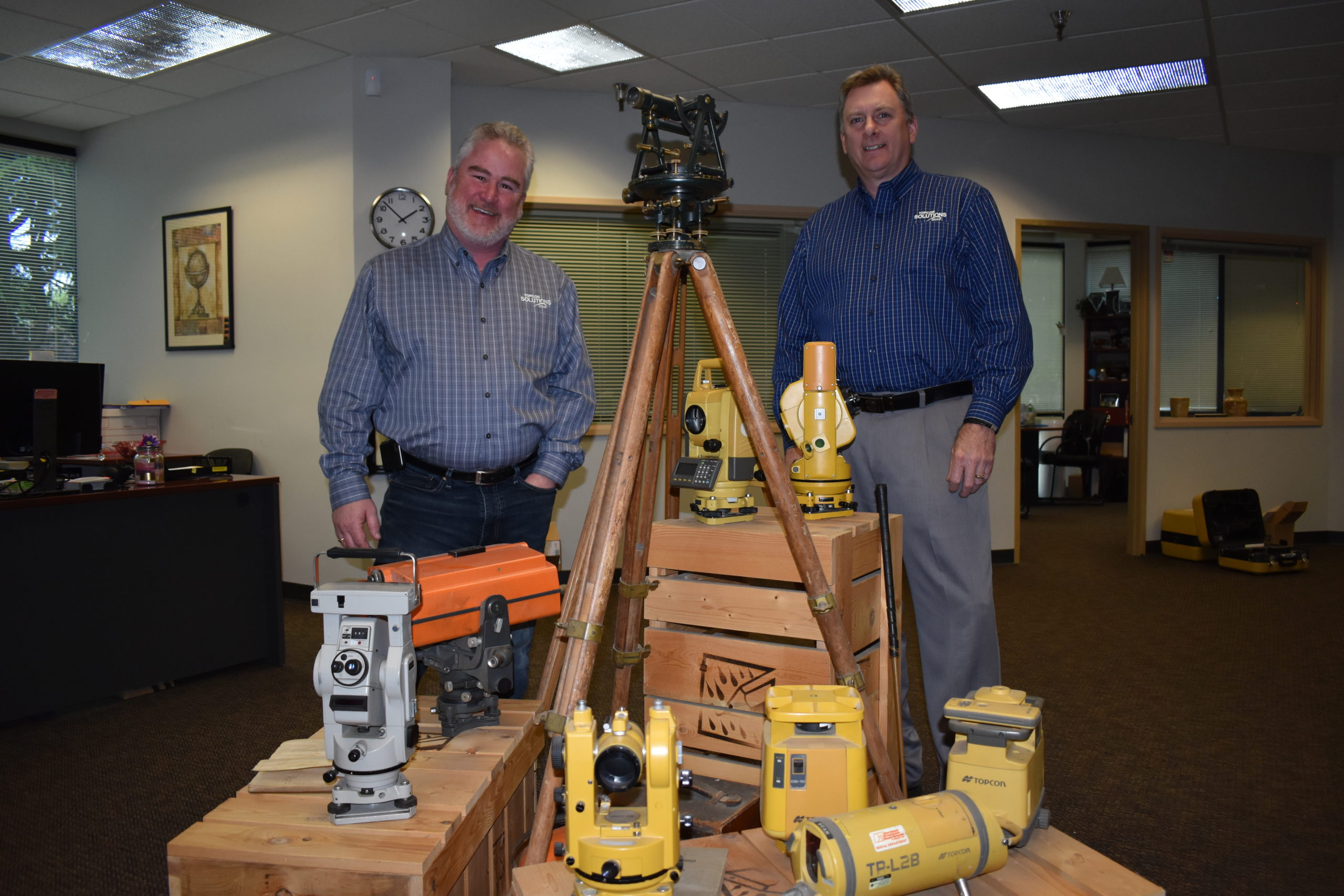 Mark Contino, vice president of North American retail distribution at Topcon Positioning Systems (left) and Ken Shersty, director of hardware sales for TSS, in a small museum of survey gear in The Solutions Store Kent, Washington, location.