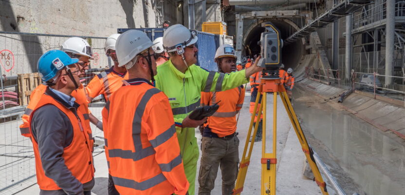 Working in the TBM access trench, a team uses a total station and handheld controller for automated measurement and data analysis.